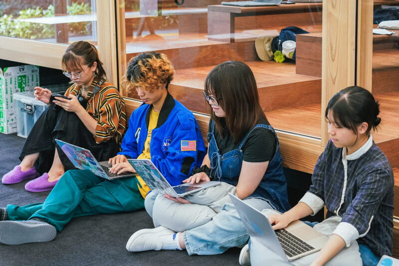 仲間と一緒にPCで作業をする様子