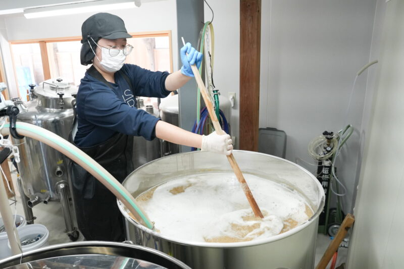 大きな樽をかき混ぜる、仕込み中の熊谷さん