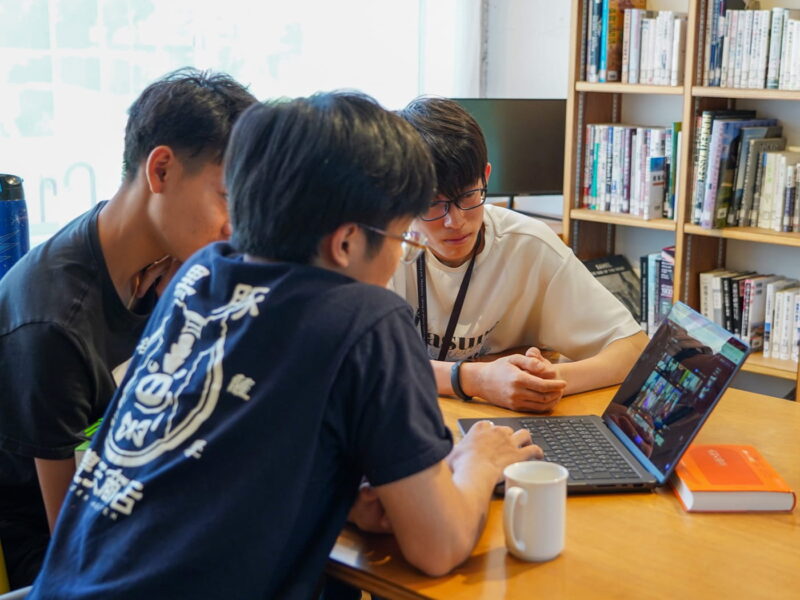 顔を寄せ合ってパソコンを見つめる学生