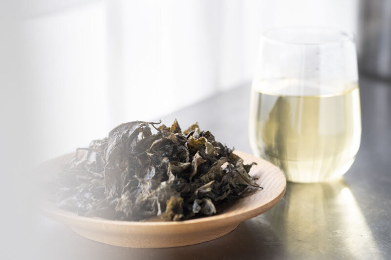 グラスに入った阿波晩茶と木皿に乗った茶葉