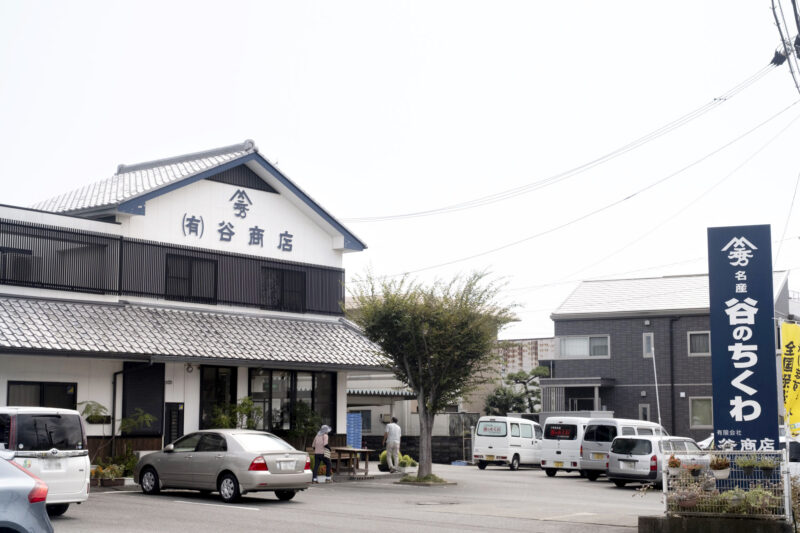 谷ちくわ商店の店舗兼工場。車が数台停まっている。