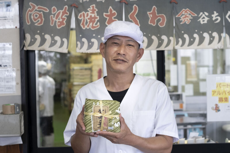 ちくわのパッケージを持ち微笑む、谷泰志さん